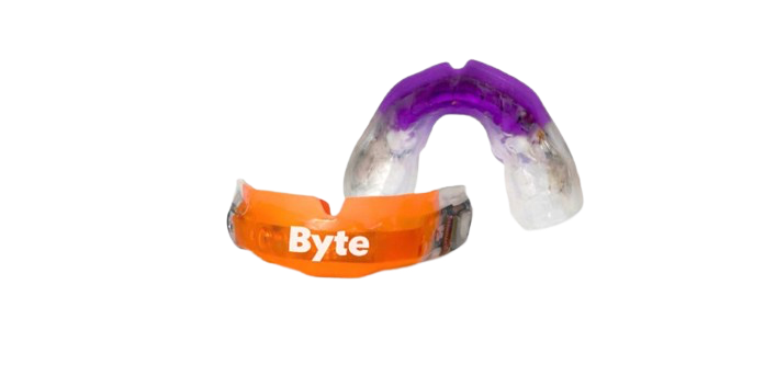 Orange Byte mouthguard with a clear purple mouthguard behind it